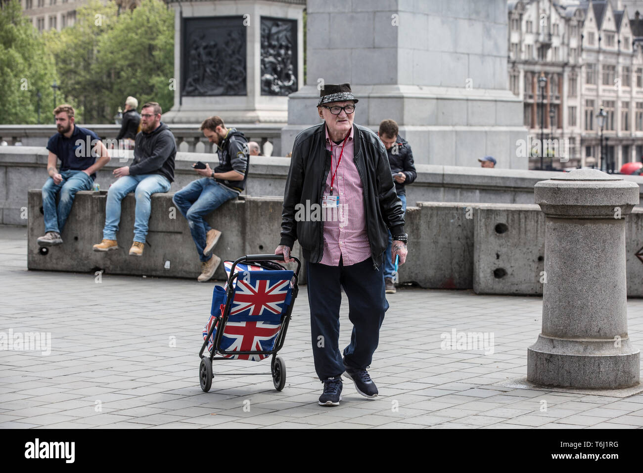 Elderly Londoner with Union Jack shopping trolley out and about in Trafalgar Square, London, England, UK Stock Photo