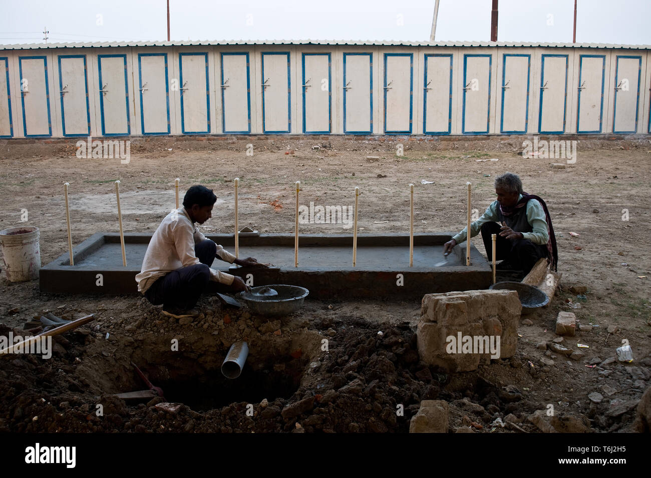 Masons are building sanitary facilities before the beginning of the Kumbh mela ( India) In the background, public toilets are visible. Stock Photo