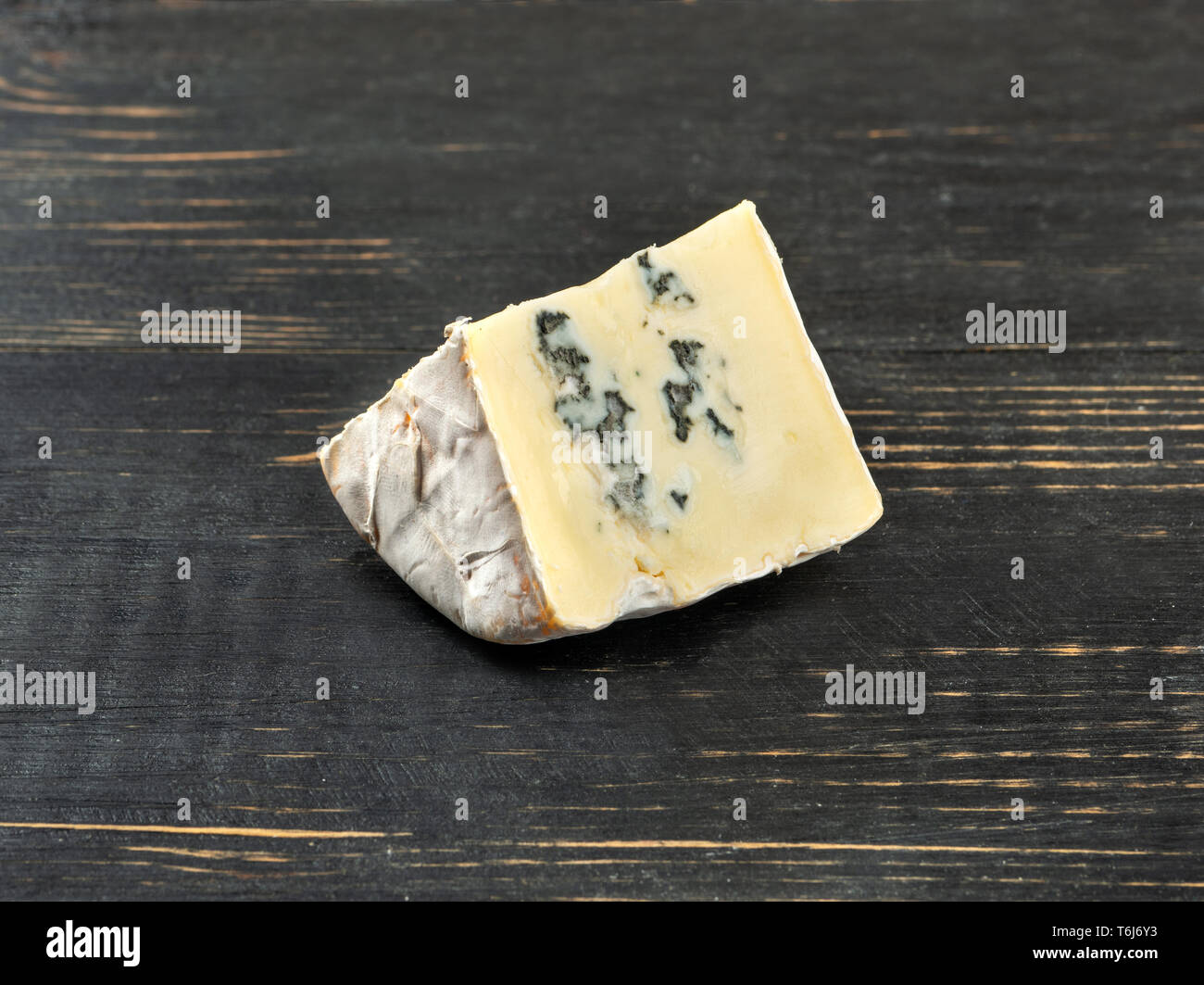 Slice of brie cheese with mold on dark wooden background Stock Photo