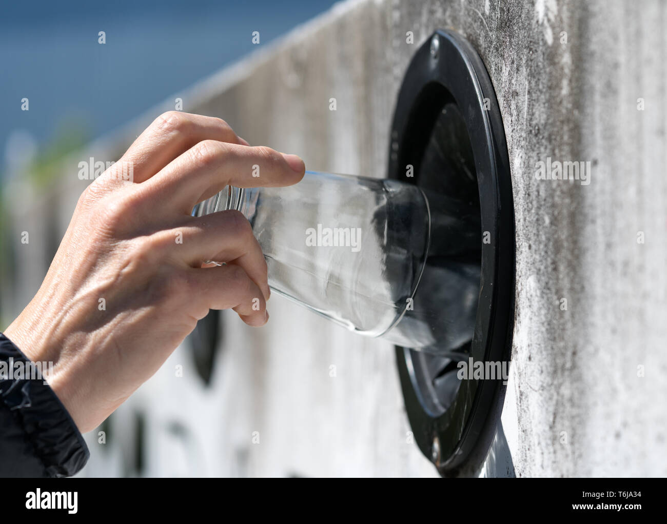 detail view of a female hand recycling glass to save the environment at her local recycling