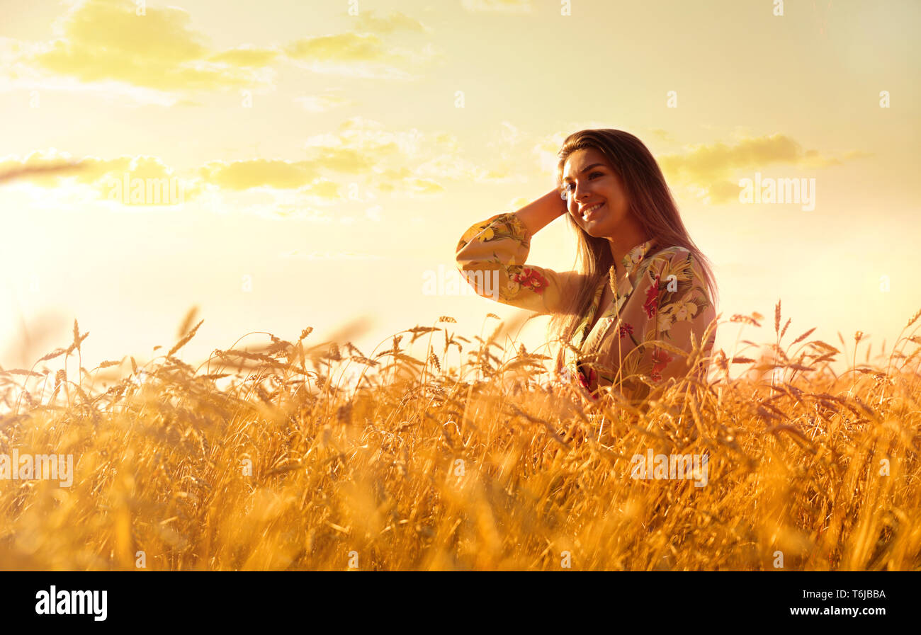 Young woman in wheat field at sunset Stock Photo - Alamy