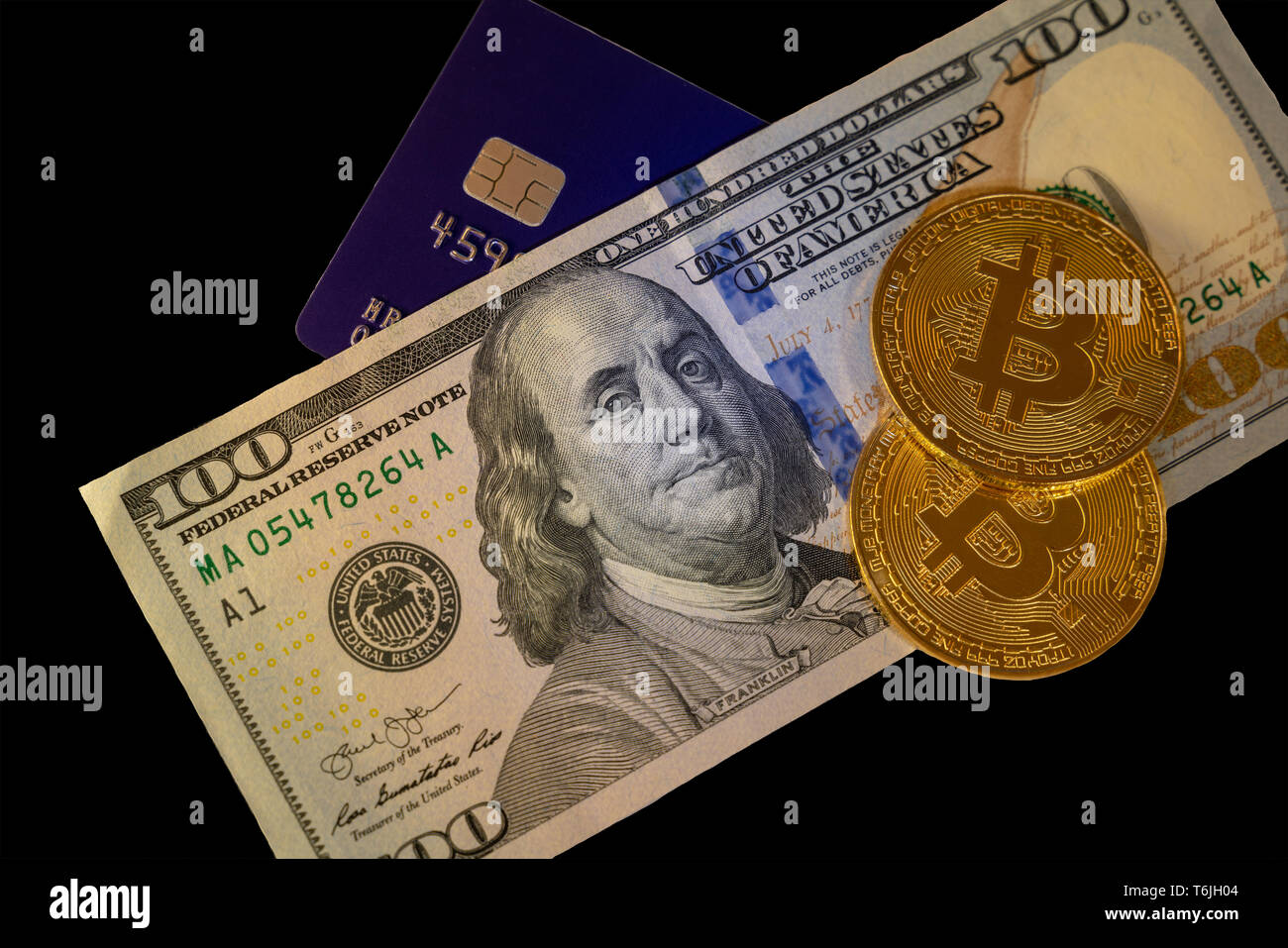 Isolated bitcoin with a blue credit card on top of hundred dollars banknote background, cryptocurrency accepting for payment and finance concept Stock Photo