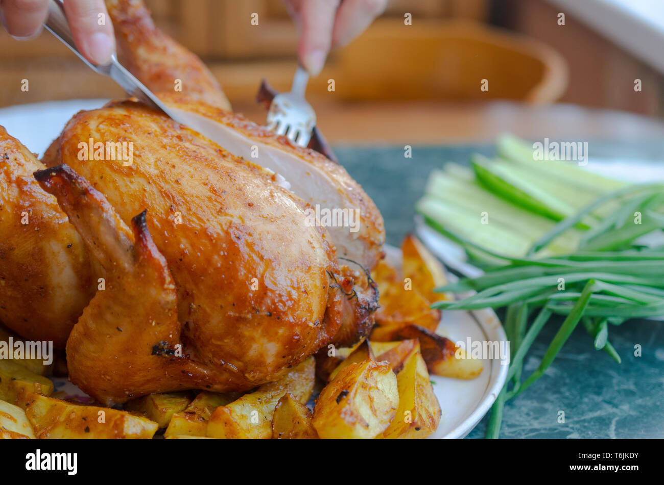 Chicken from the oven on a white plate with greens and potatoes with a golden crust Stock Photo