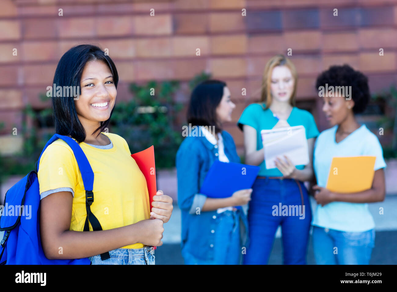 Native latin american female student with group of students outdoor in summer at university Stock Photo