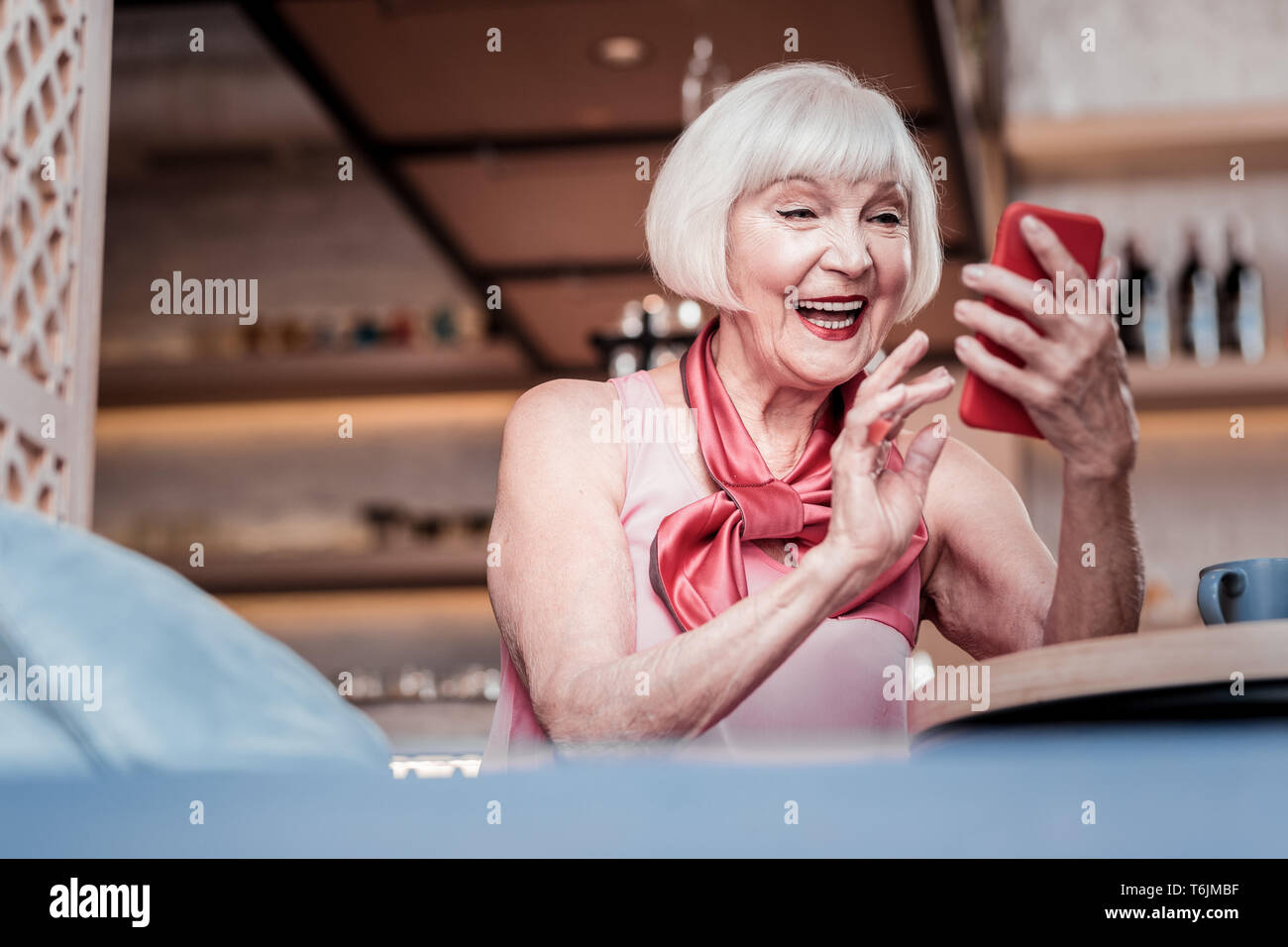 Excited old lady with bob haircut observing received message Stock Photo