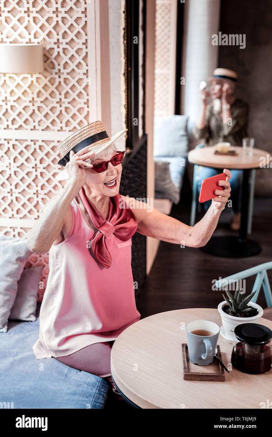 Active old lady visiting stylish cafe and making selfie Stock Photo