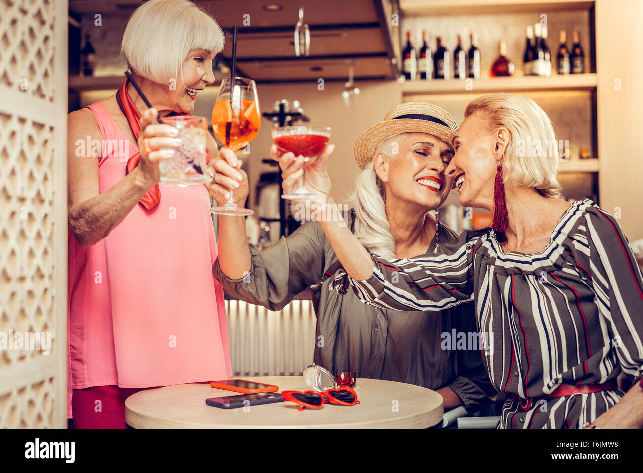 Friendly pleasant old ladies in stylish outfits drinking cocktails Stock Photo