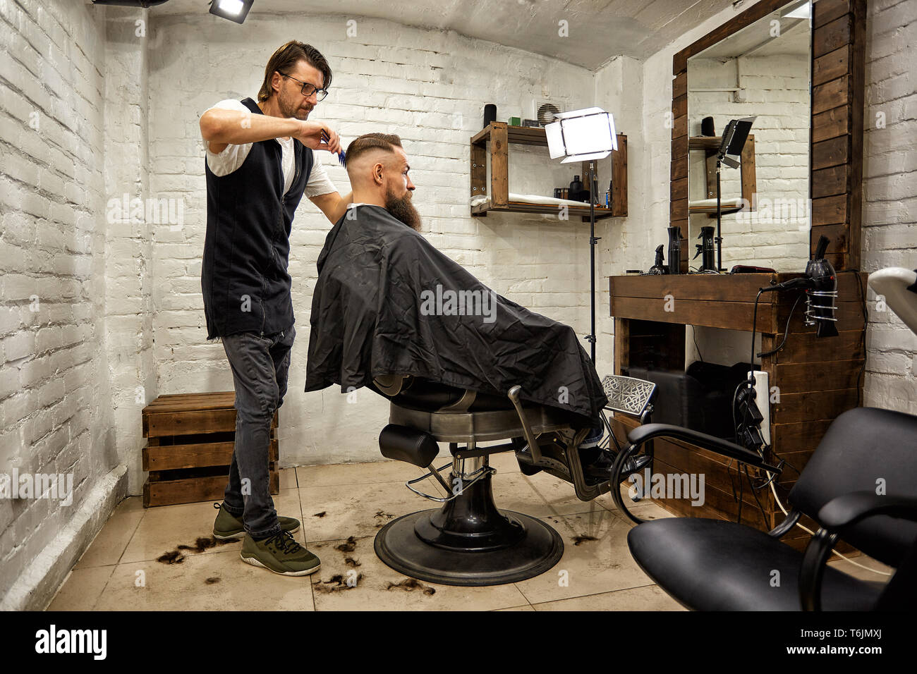 Brutal guy in modern Barber Shop. Hairdresser makes hairstyle a
