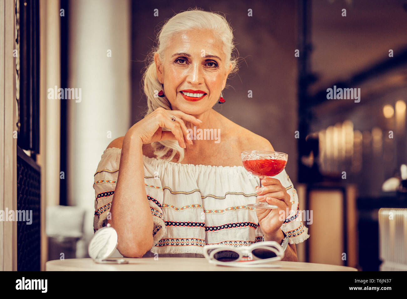 Smiling grey-haired woman with red lips wearing off-shoulder blouse Stock Photo