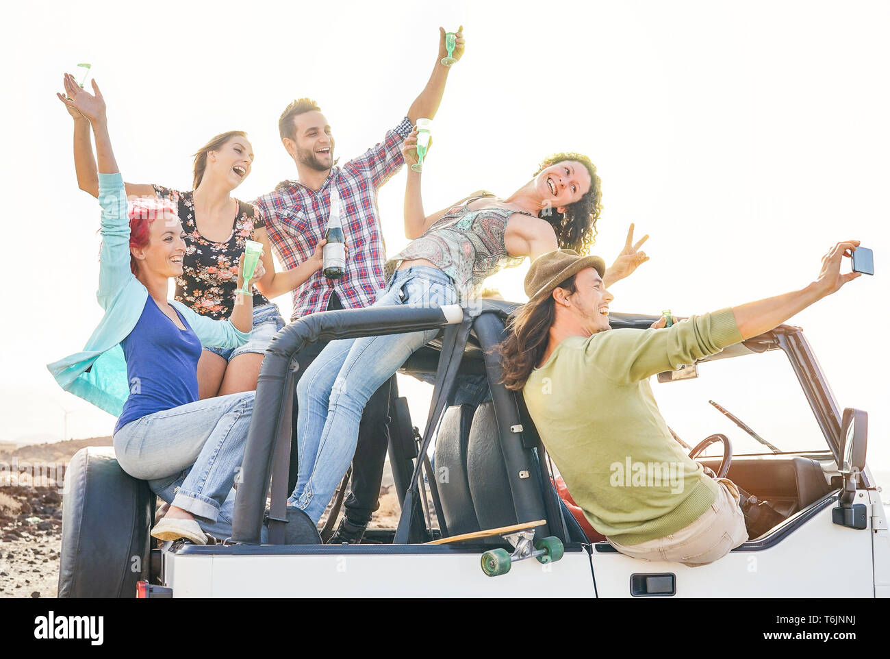 Group of happy friends taking selfie with mobile smart phone on convertible car - Young people having fun making party during their road trip Stock Photo