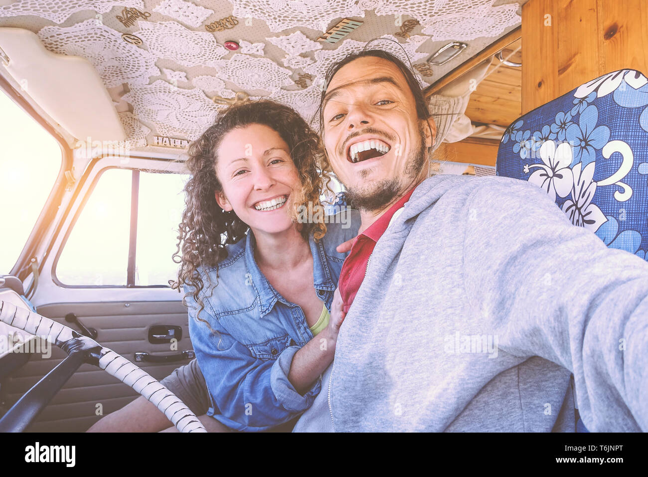 Happy couple taking a selfie inside a vintage minivan - Travel people excited and ready for driving to road trip with a van camper Stock Photo