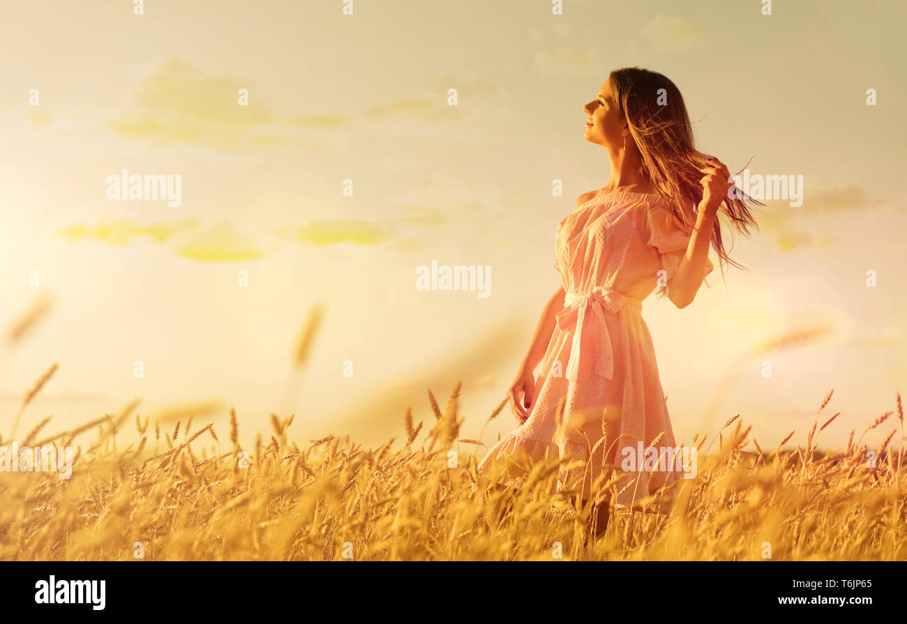 Young woman in wheat field at sunset Stock Photo - Alamy