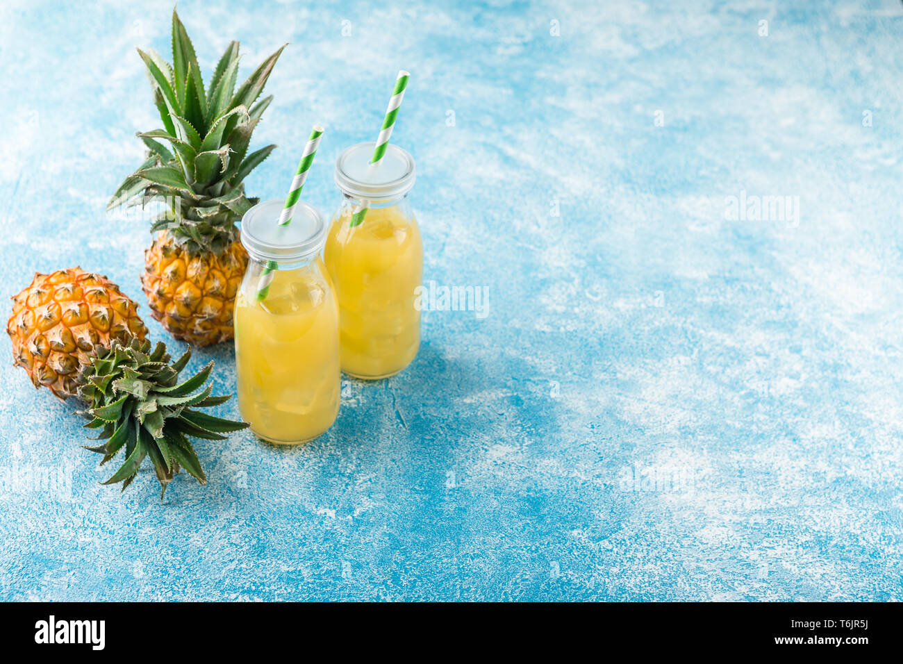 Fresh pineapple juice and ripe pineapple on grey background Stock Photo