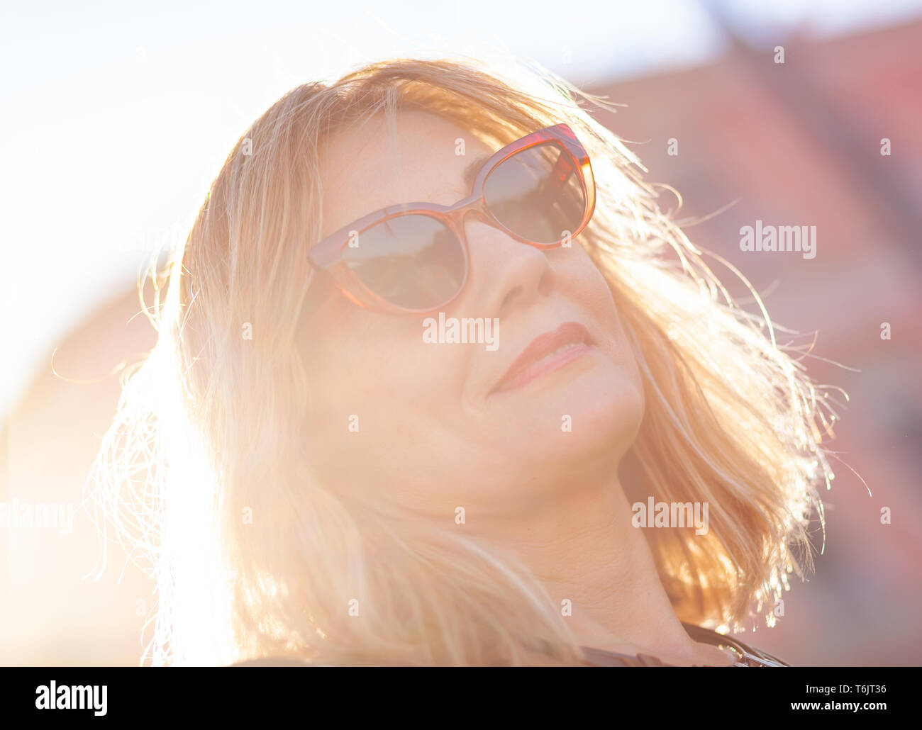 Close up portrait of an attractive woman with red sunglasses and blonde hair. Stock Photo