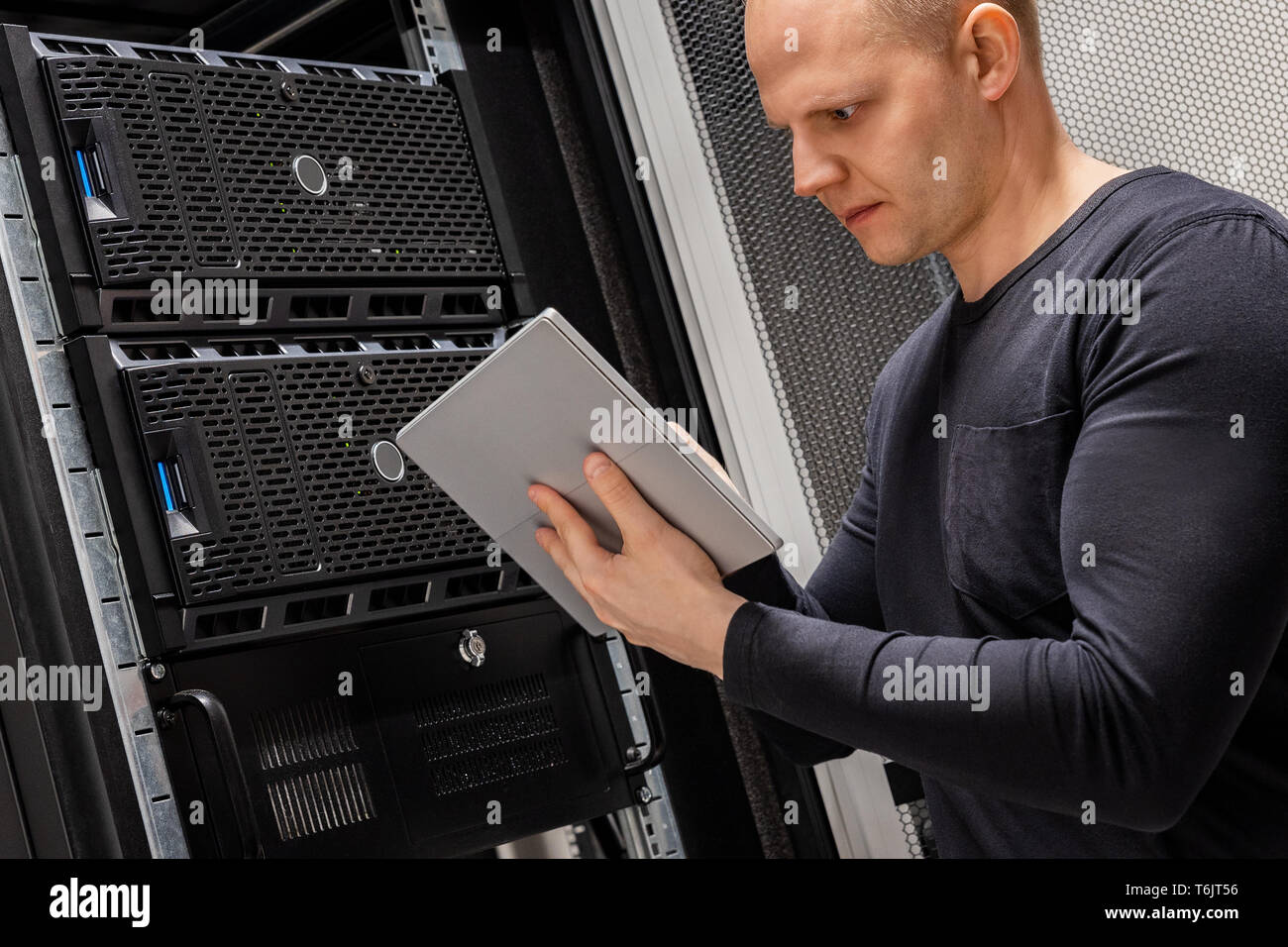 Male Technician Holding Digital Tablet Analyzing Servers in Datacenter Stock Photo