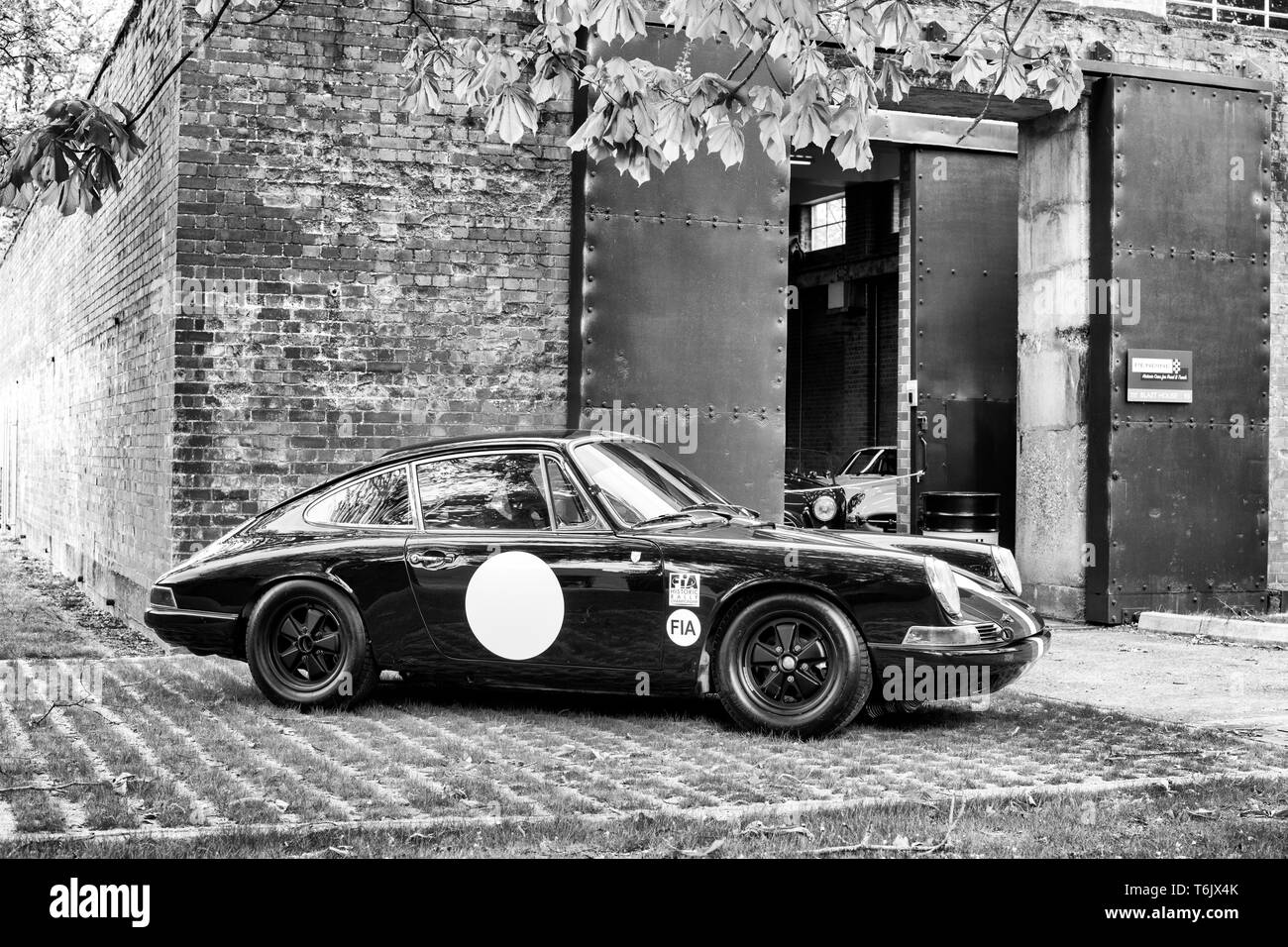 1965 Porsche 911 SWB Competition Car in front of a workshop at Bicester heritage centre ‘Drive It Day’.Bicester, Oxfordshire, England. Black and White Stock Photo