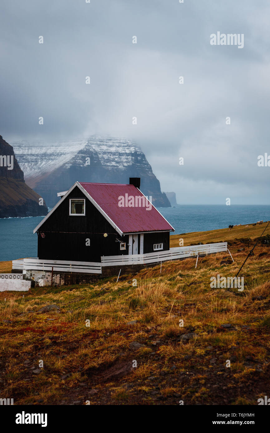 Typical Faroese black wooden house with colourful roof in the village
