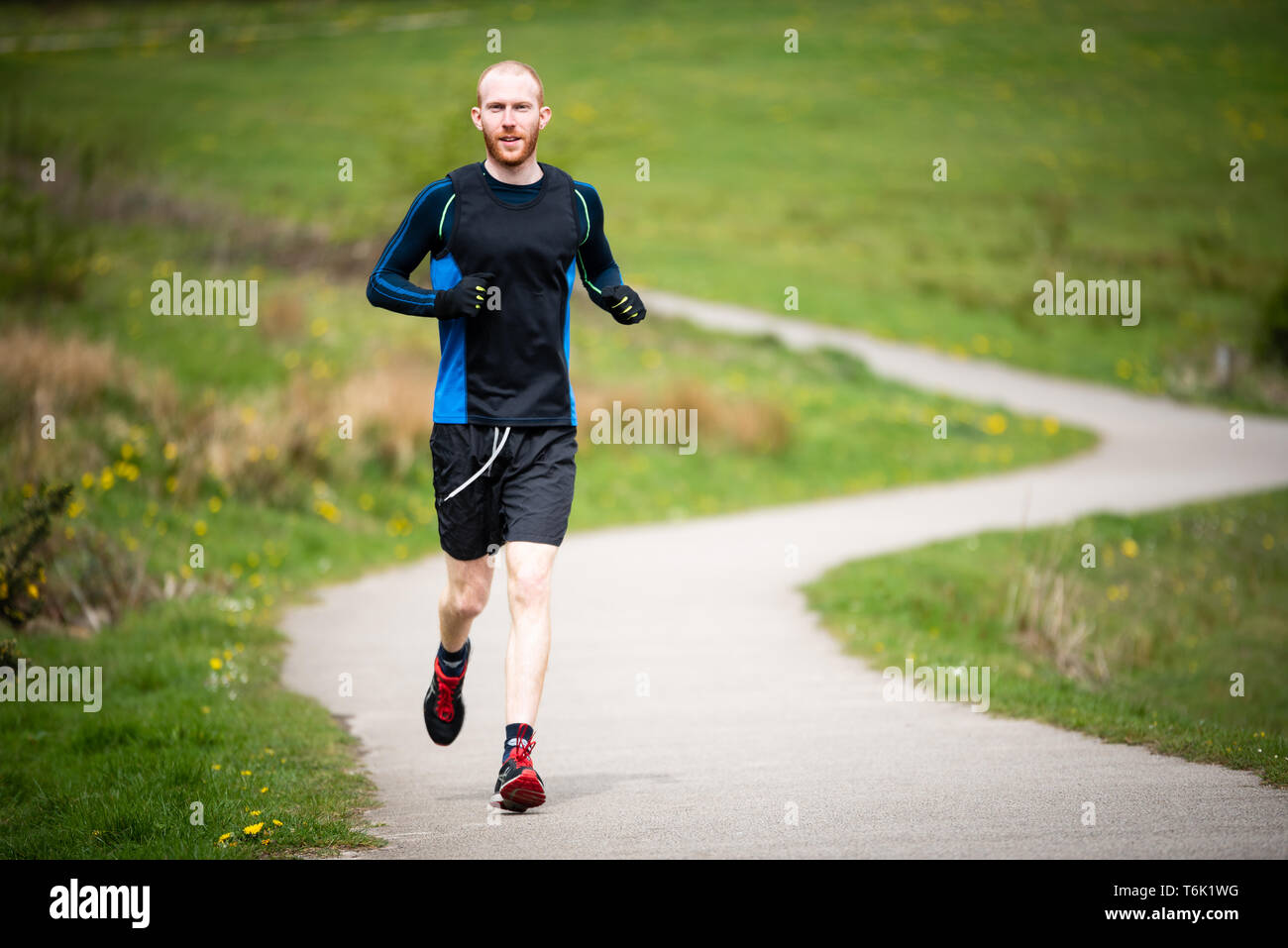 Young man in mid 20s exercising and keeping fit by running in a park Stock Photo