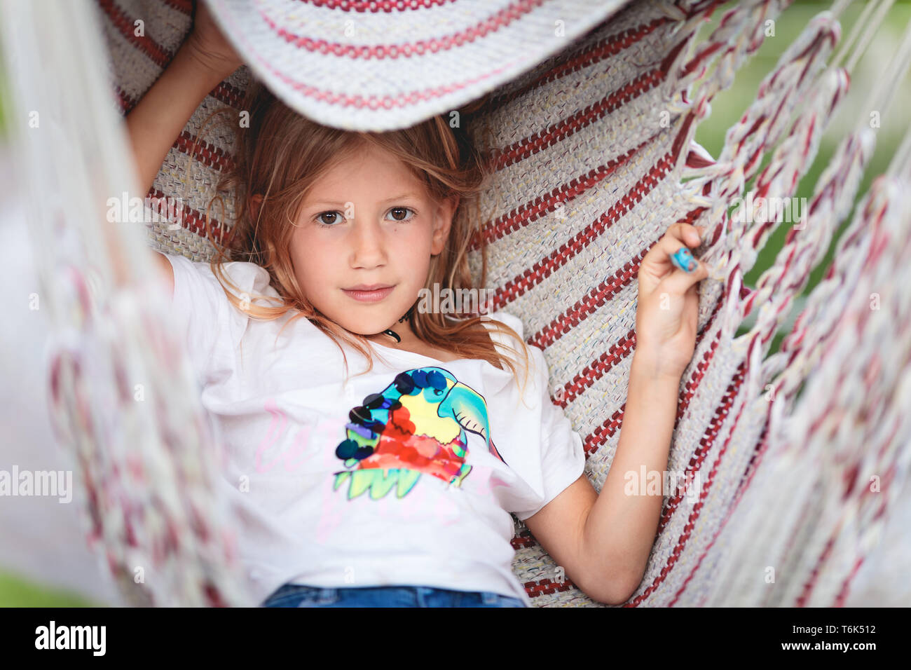 Young Caucasian girl lying in red striped hammock Stock Photo