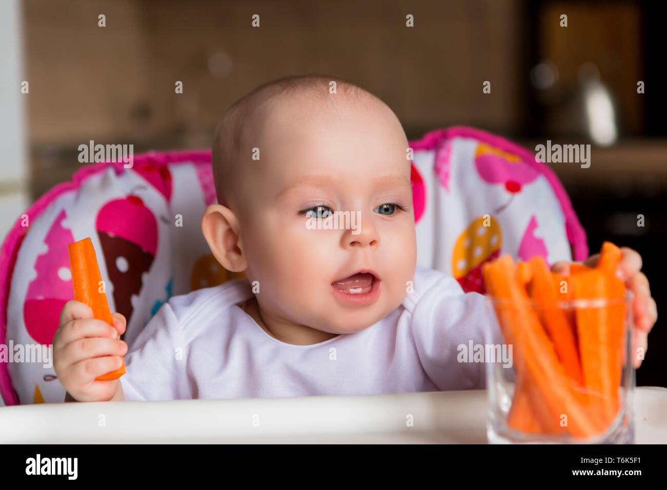 baby in a child seat eating vegetables.baby in the baby chair eating