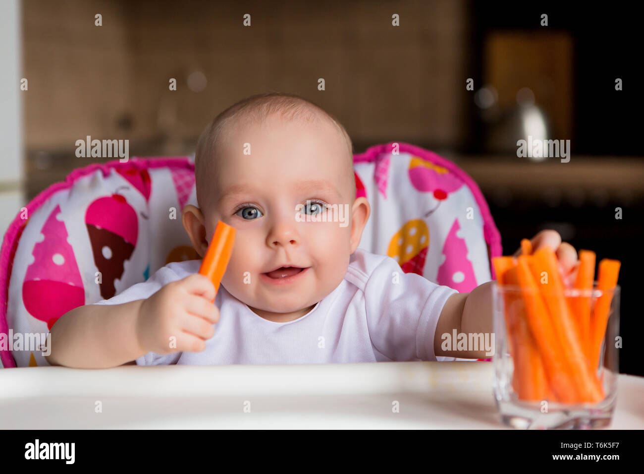 baby in a child seat eating vegetables.baby in the baby chair eating