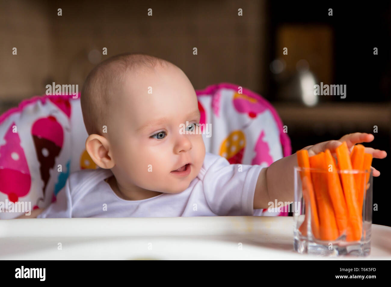 baby in a child seat eating vegetables.baby in the baby chair eating