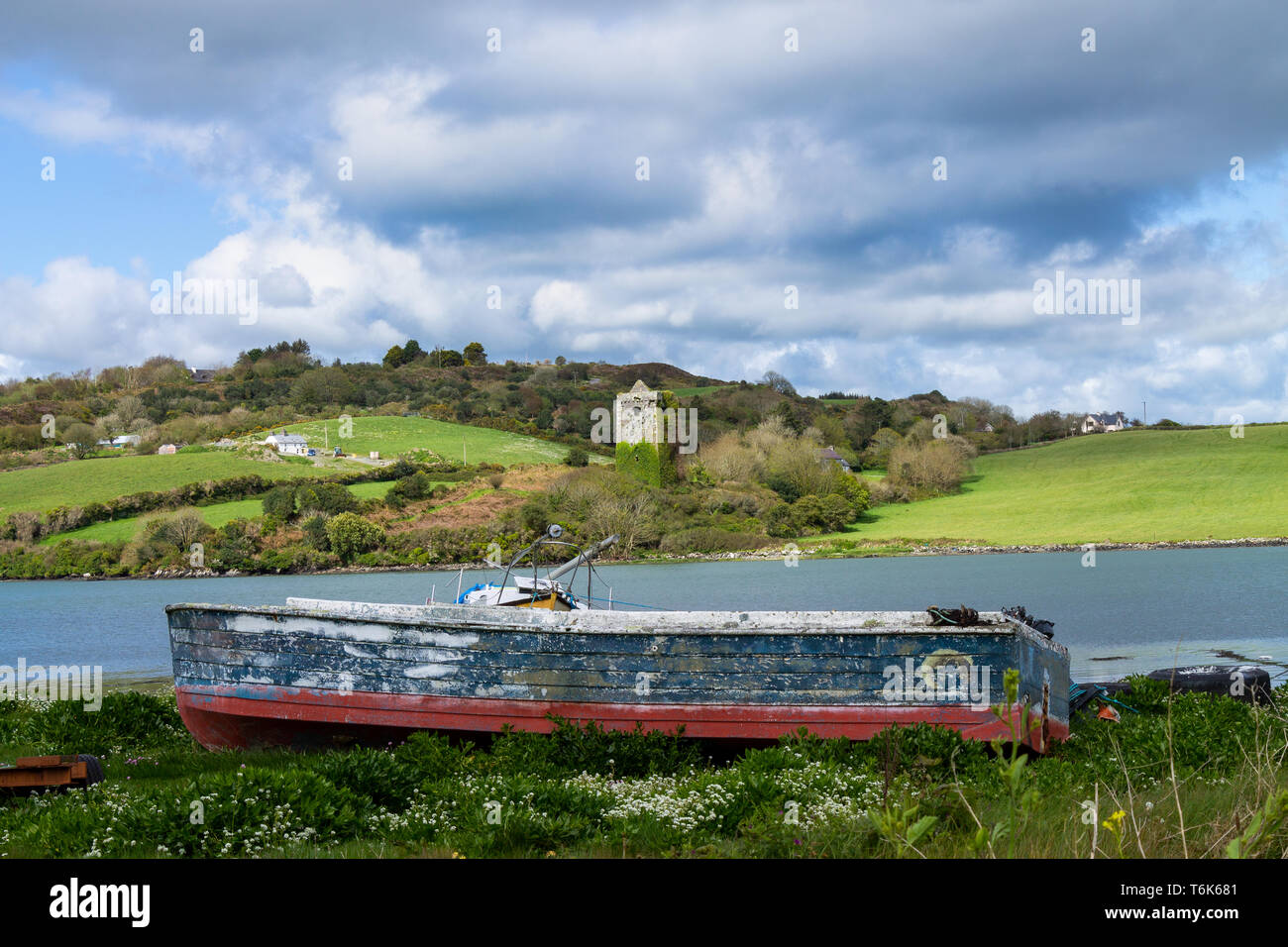 Wrecked boat on the foreshore with a castle tower in the background. Stock Photo