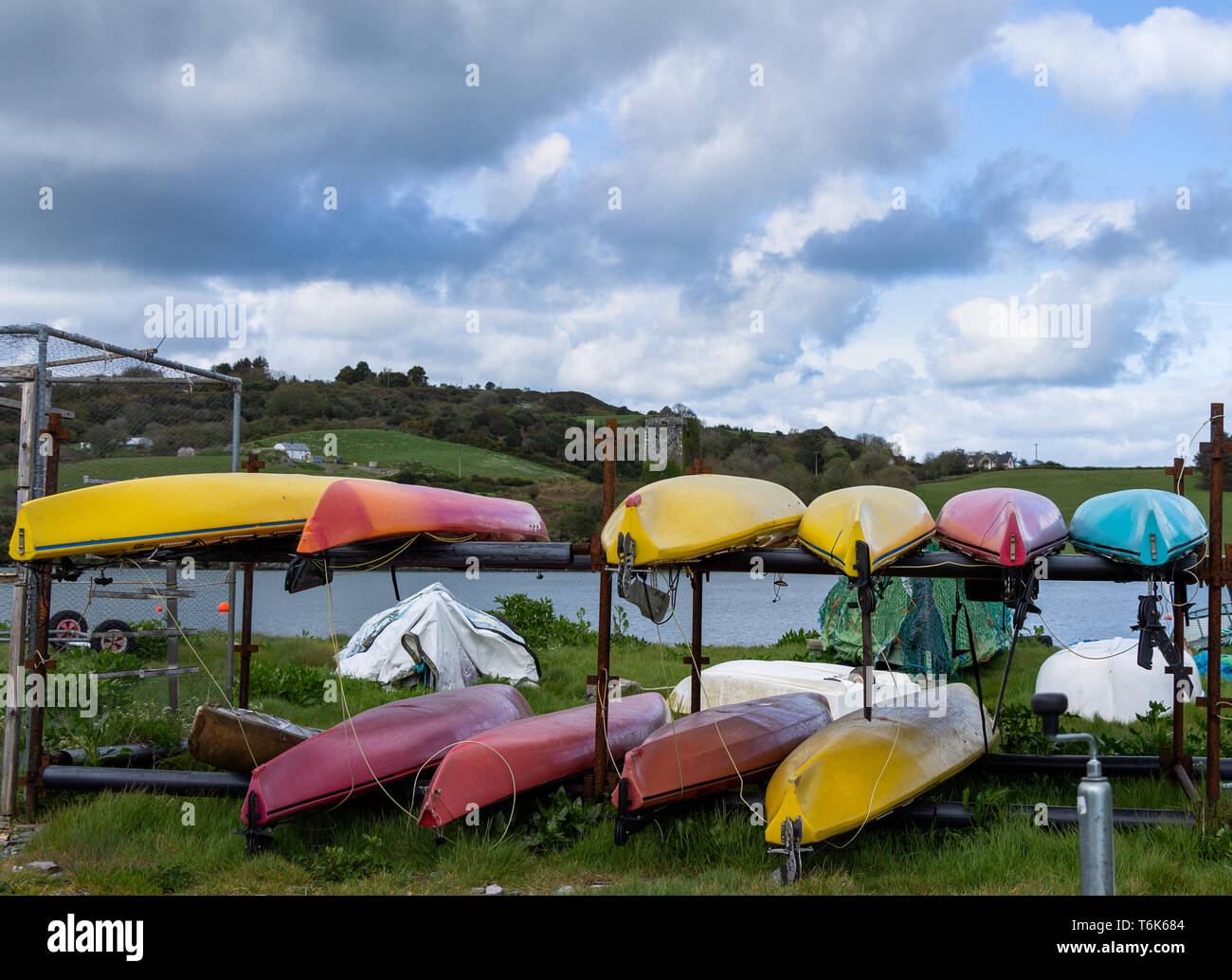 multi coloured canoes on racks on the foreshore with a castle tower in the background. Stock Photo