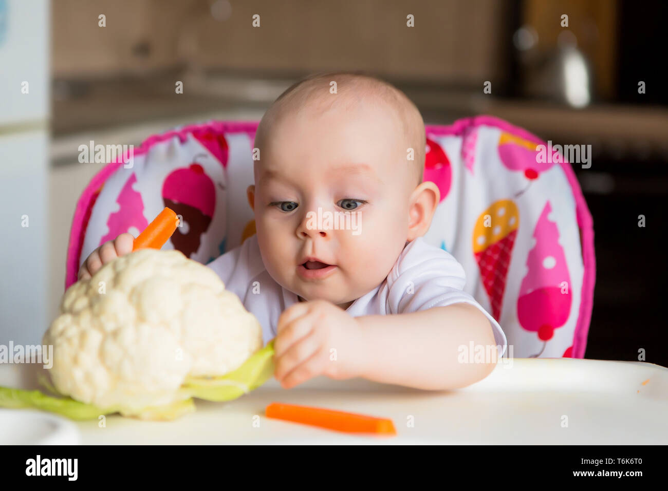 baby in a child seat eating vegetables.baby in the baby chair eating