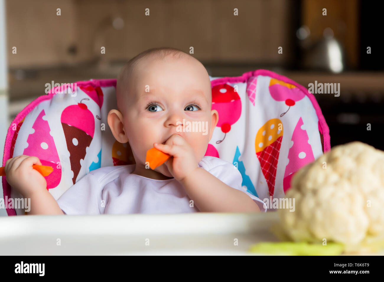 baby in a child seat eating vegetables.baby in the baby chair eating