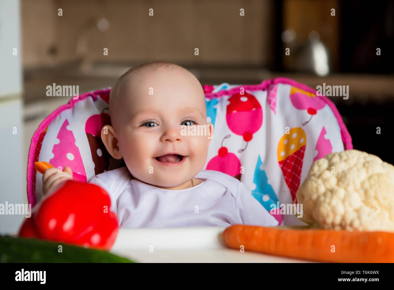 baby in a child seat eating vegetables.baby in the baby chair eating
