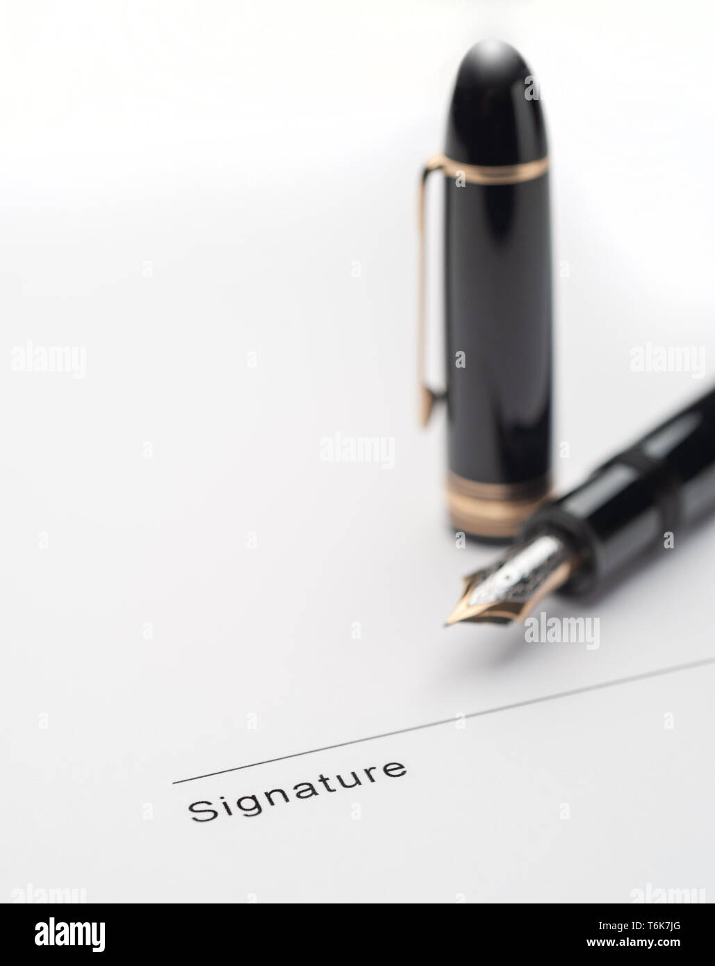 Black fountain pen on document pointing to signing area Stock Photo