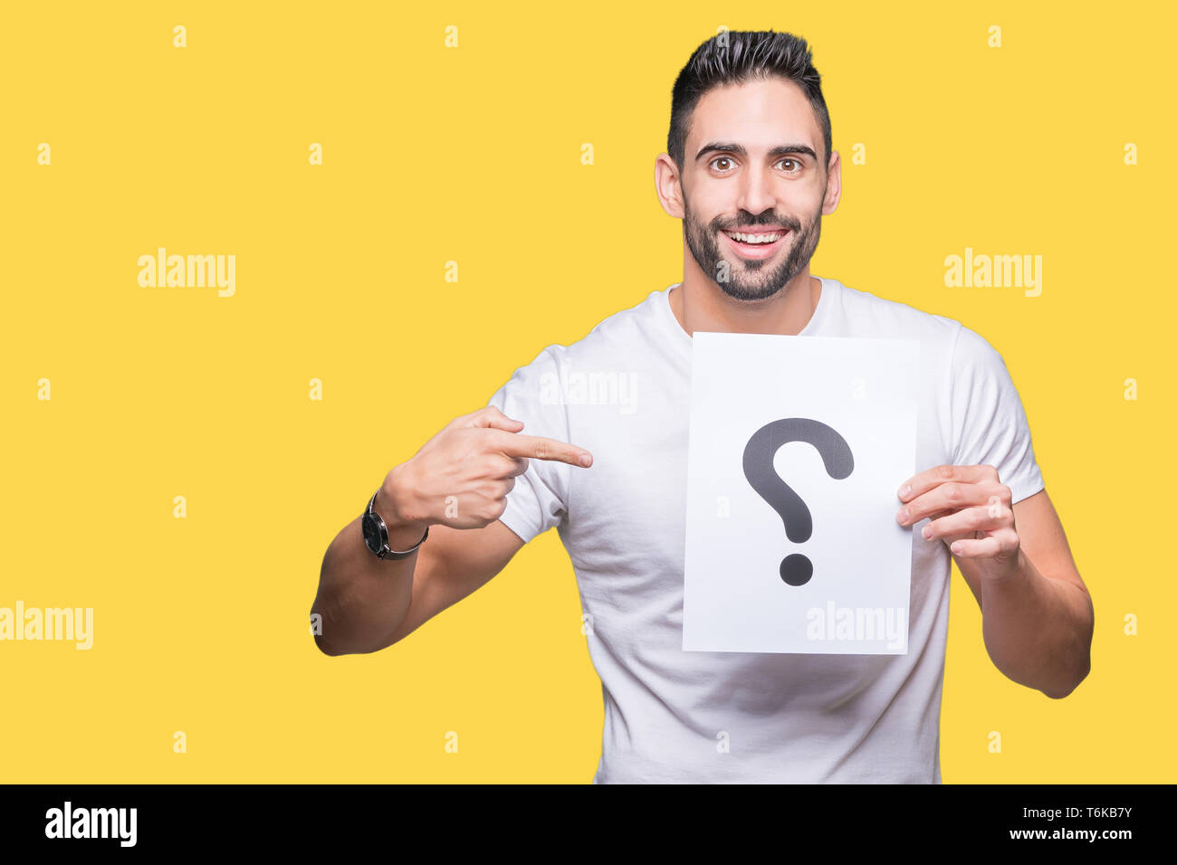 Handsome young man holding paper with question mark over isolated ...