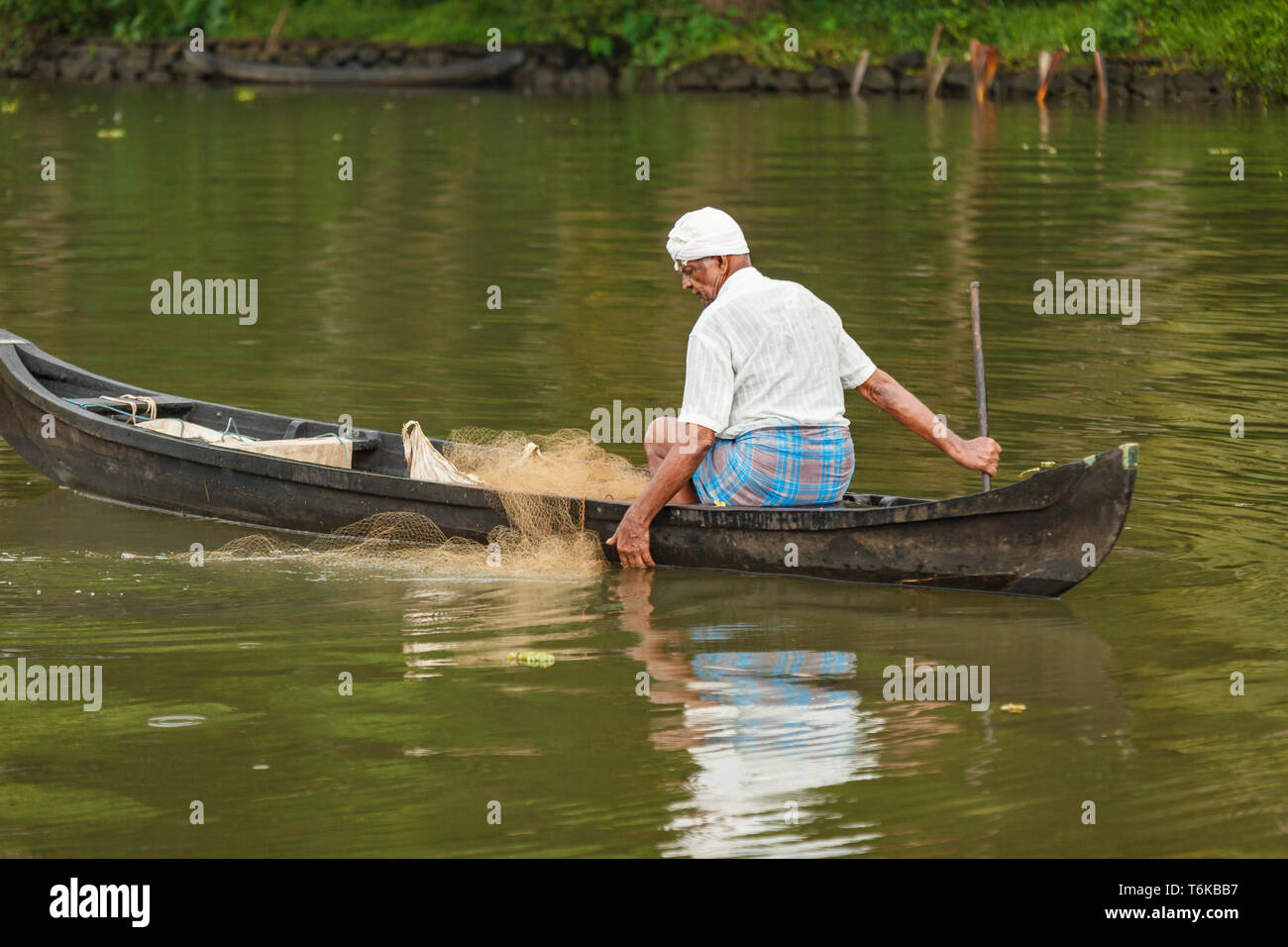 Man in traditional native dress fishing with nets in the jungle river