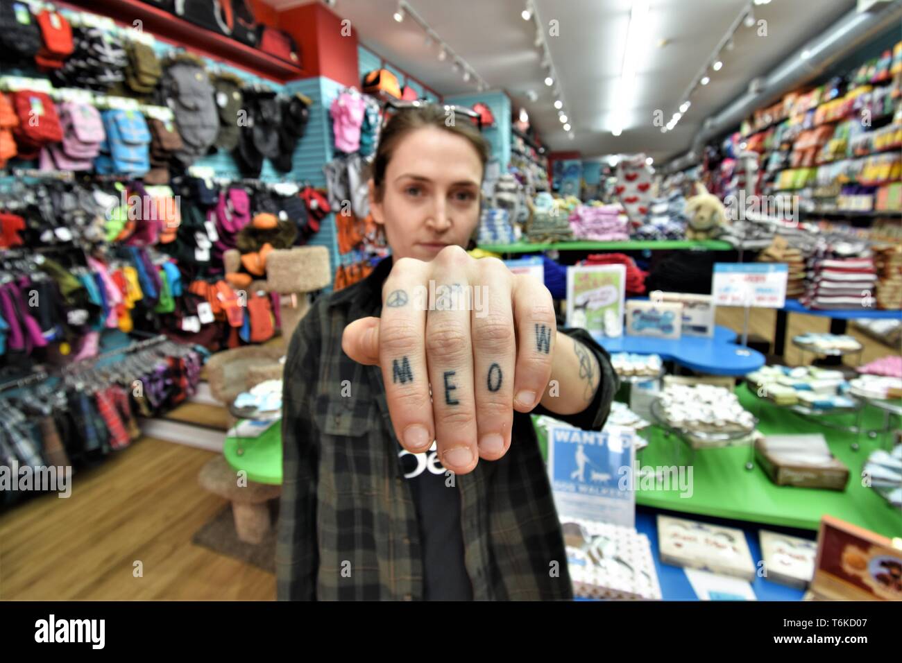 Real young sales person Woman in pet store with MEOW tattooed on her hands where supplies for dogs and cats are sold Stock Photo