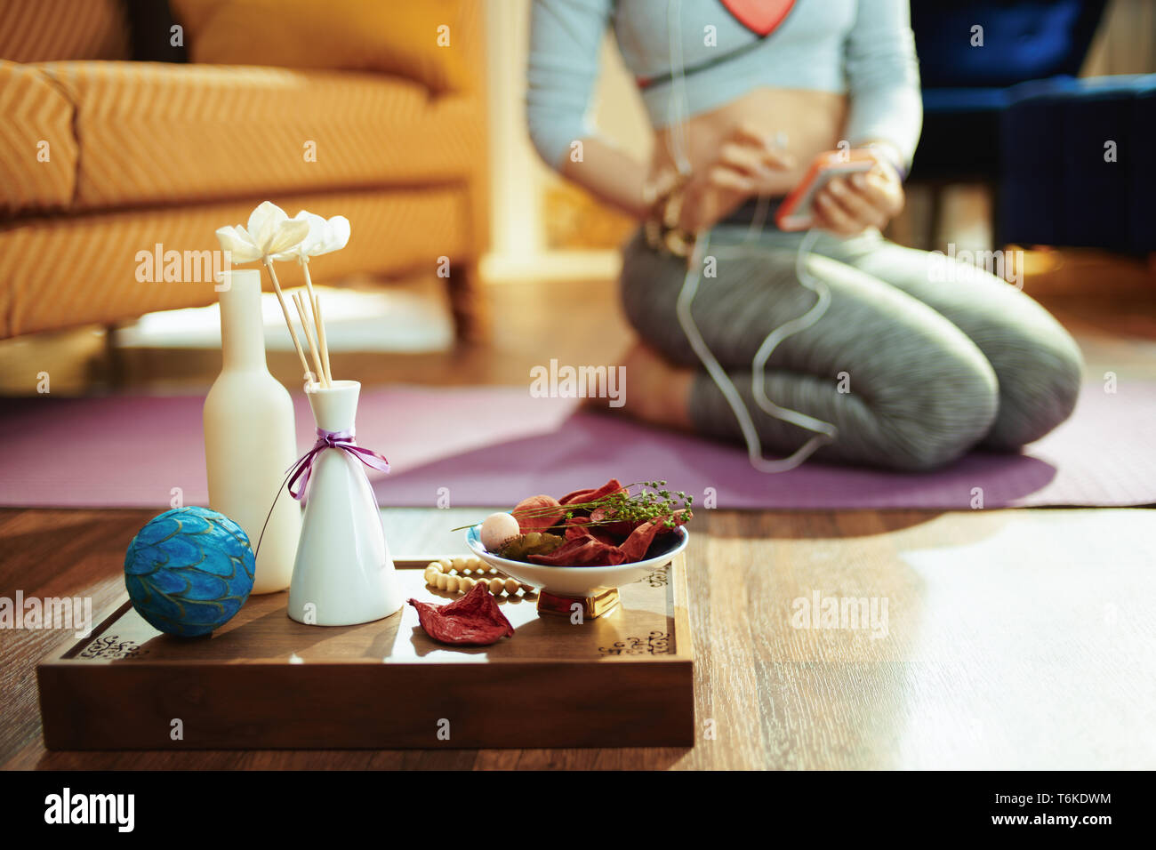 Closeup on tray with fragrant stuff for aroma yoga and fit woman choosing music for meditation in background in the modern house. Stock Photo