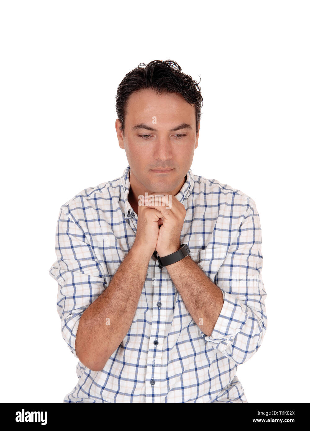 Young man praying with his hands under his chin Stock Photo