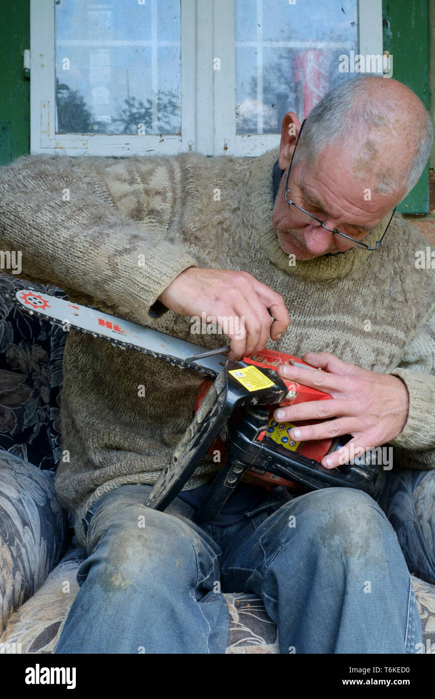 mature man working on a chainsaw to replace the blunt chain with a sharp one zala county hungary Stock Photo