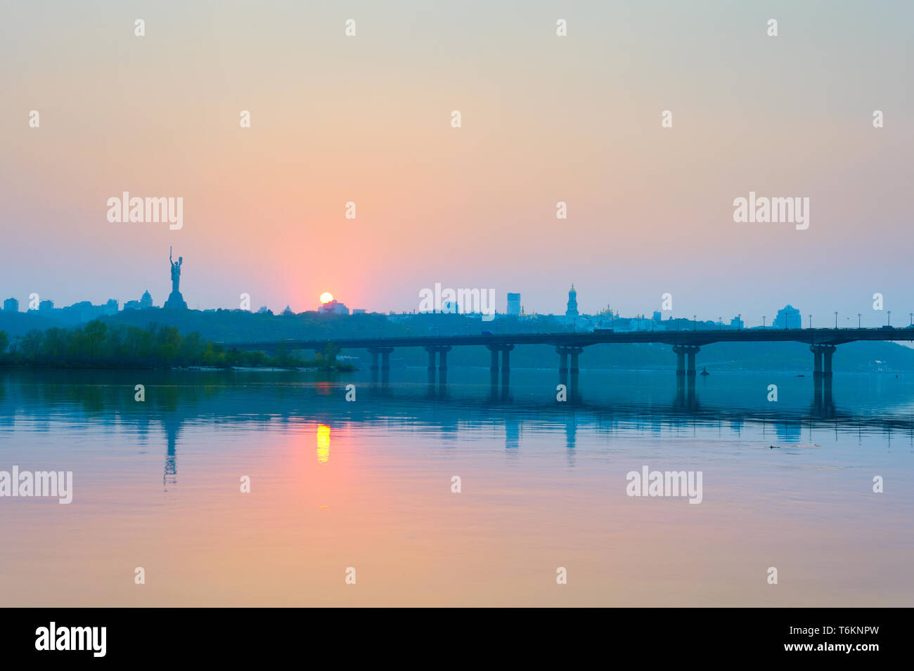 View of Mother Motherland monument above Dnipro river with Paton bridge and Kiev city at sunset, Ukraine Stock Photo