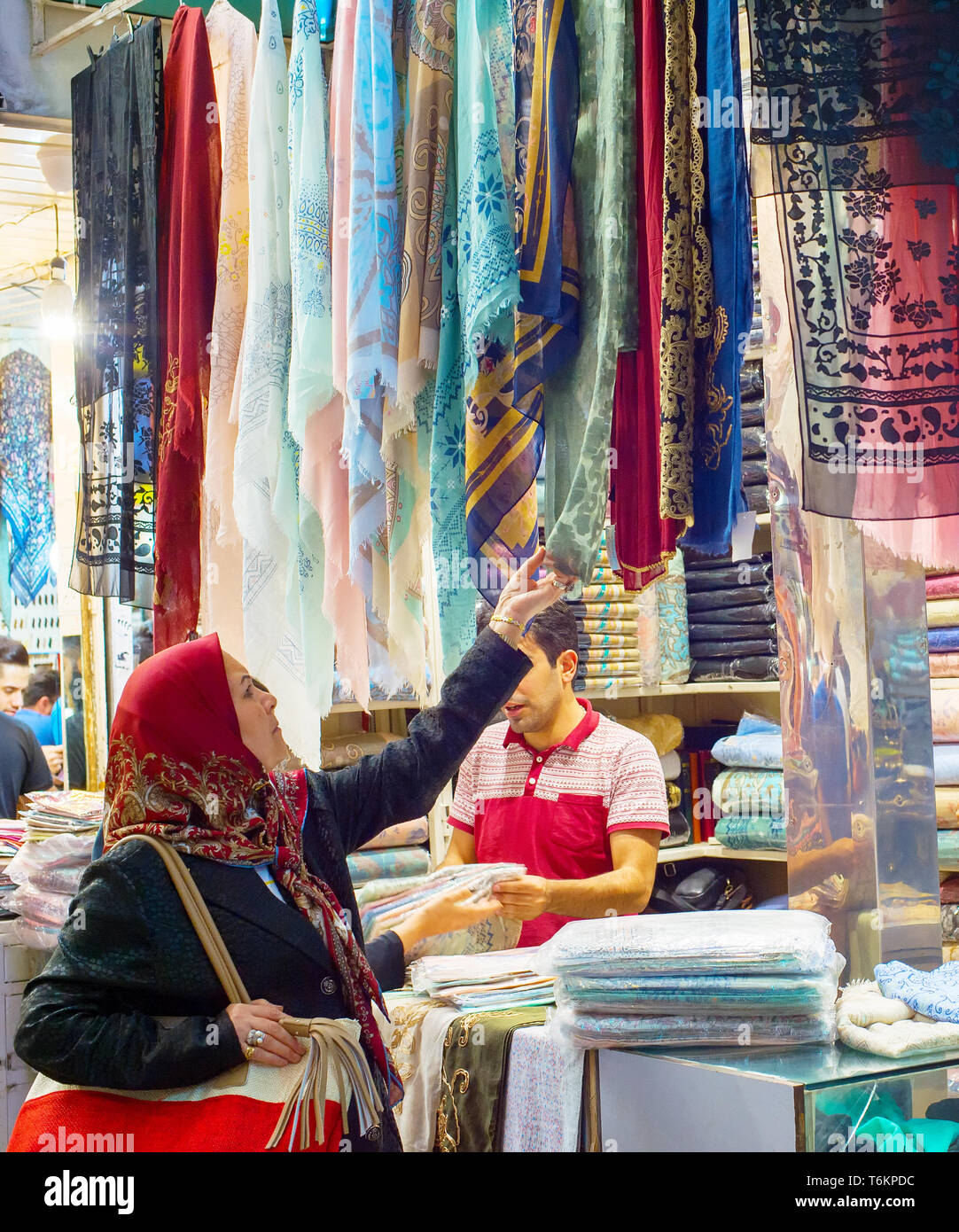 TEHRAN, IRAN - MAY 22, 2017: Woman looking at silk fabrics, textiles and colorful shawls at Grand Bazaar - main market in Tehran Stock Photo