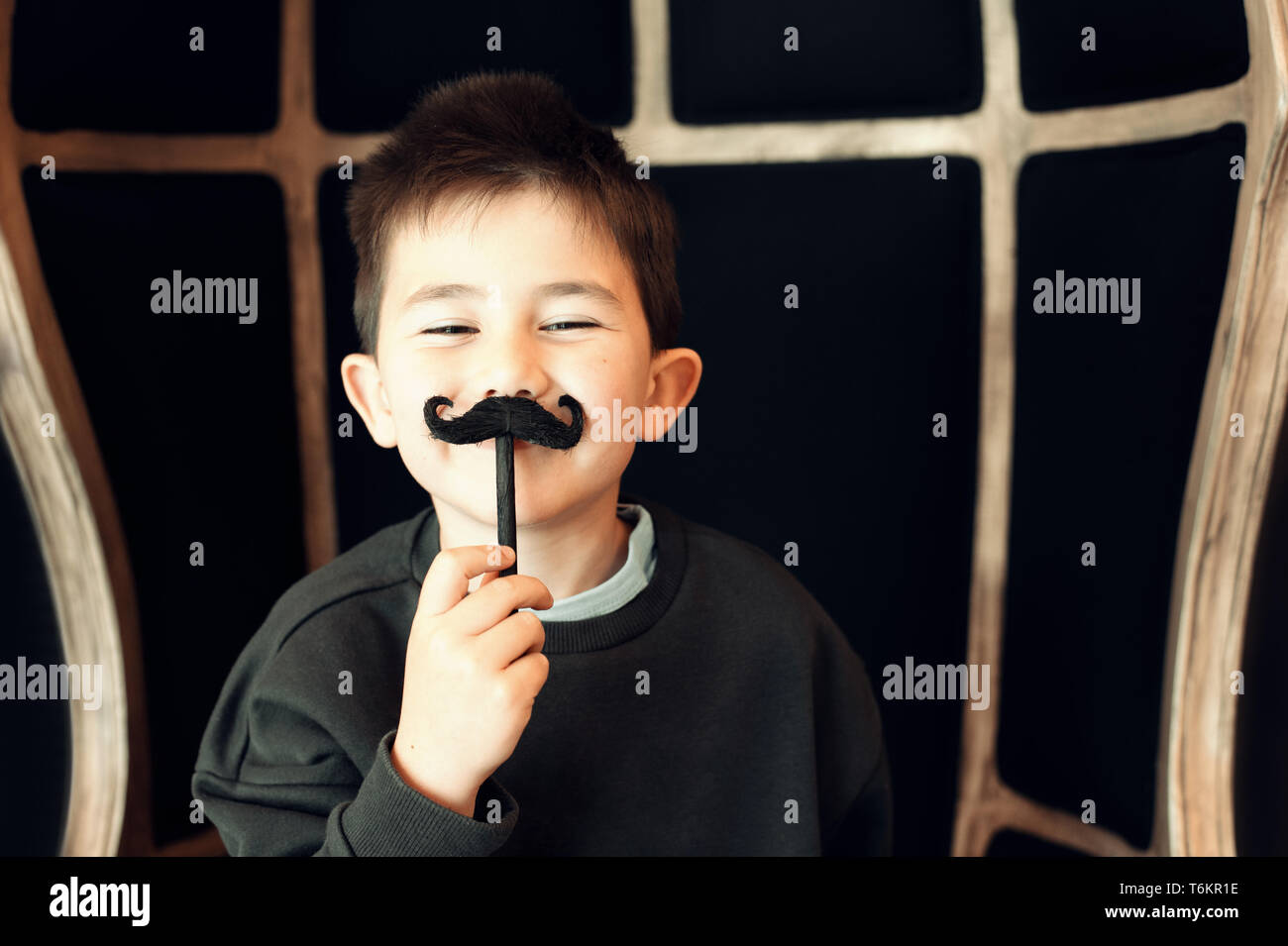 Happy kid posing with a fake moustache on black background Stock Photo