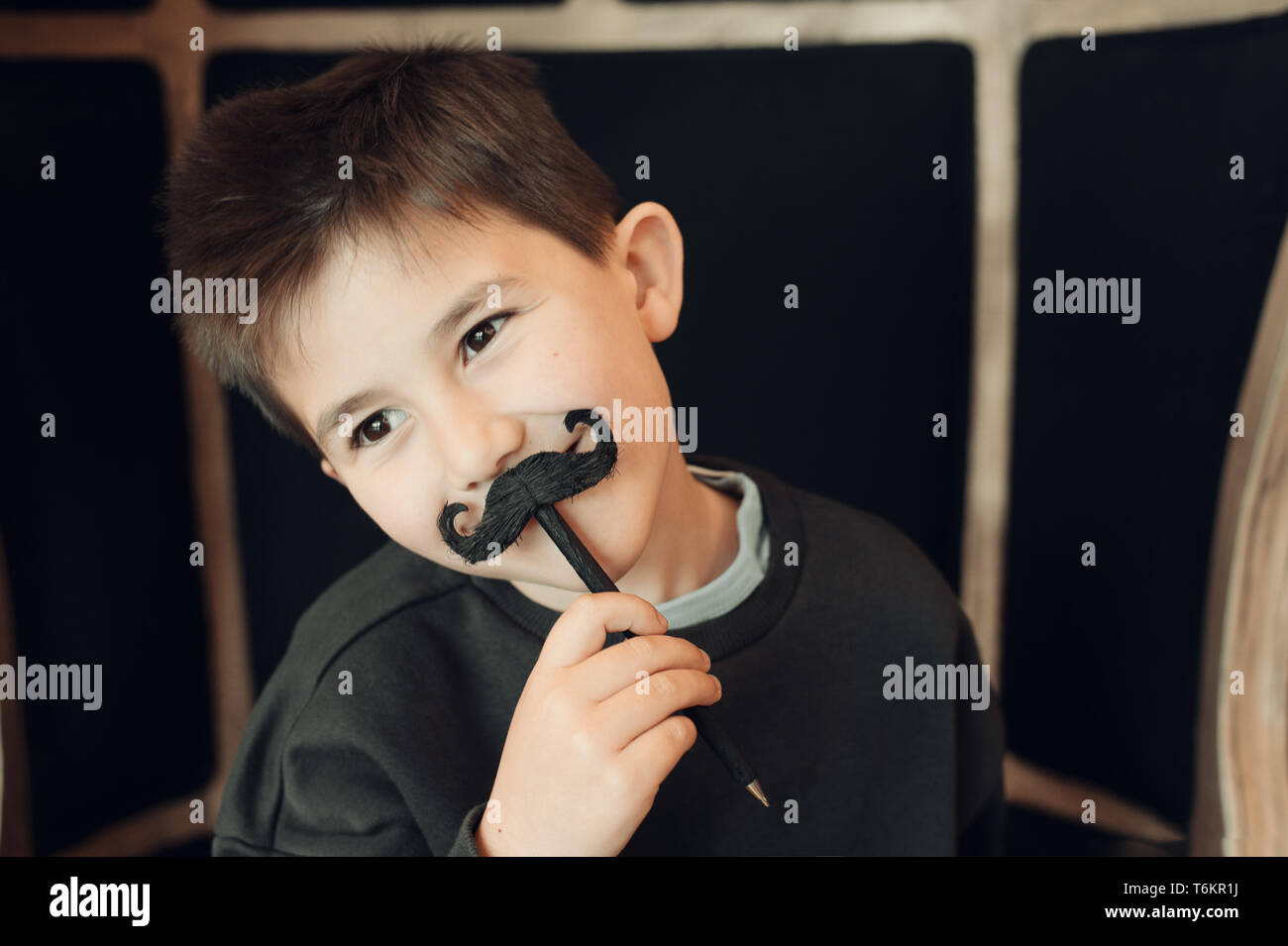 Happy kid posing with a fake moustache on black background Stock Photo