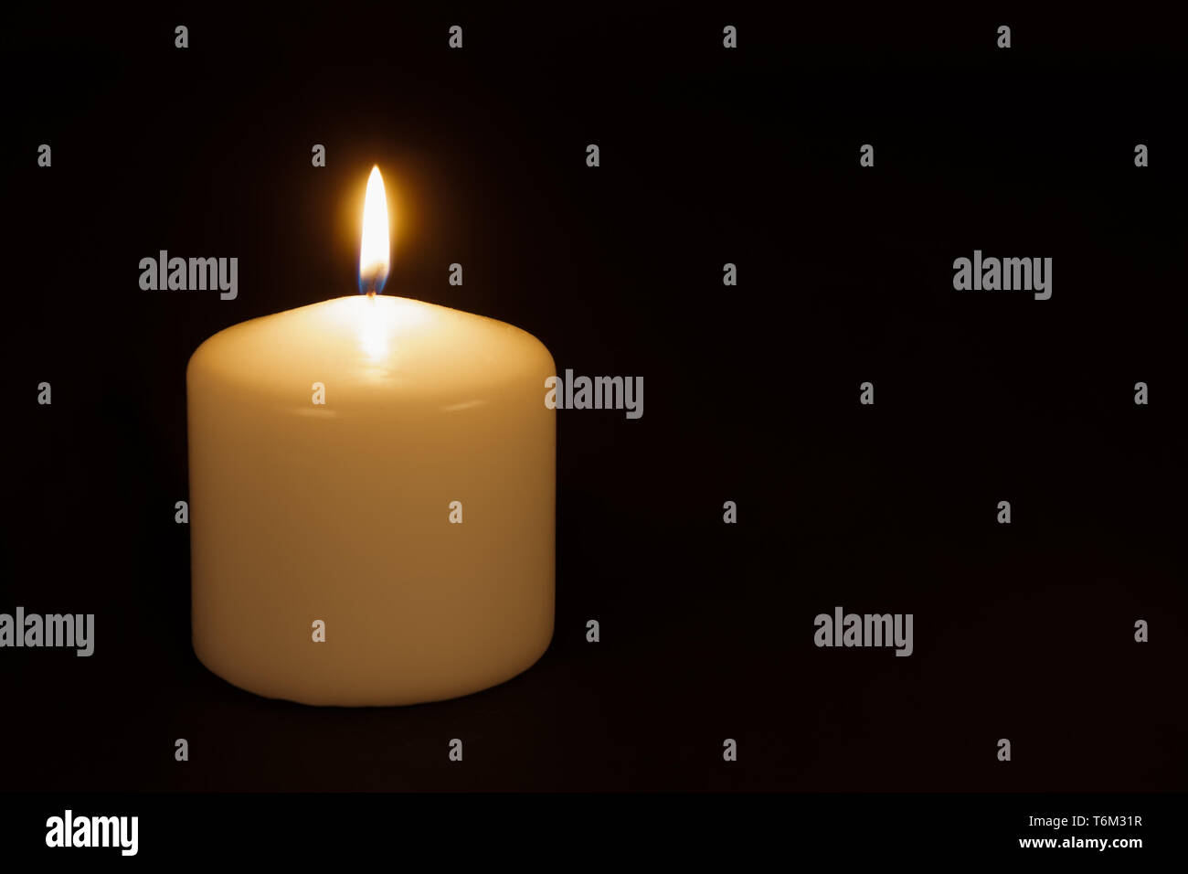 White candle burning against a black background Stock Photo Alamy