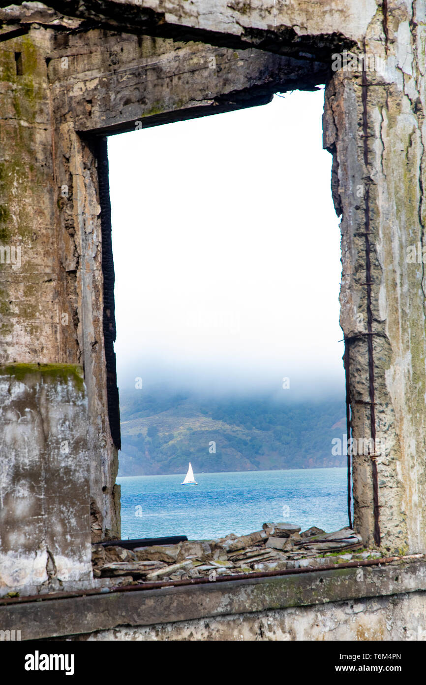 The view of a boat sailing from a window on Alcatraz Island Stock Photo