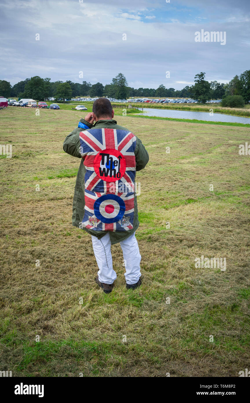 Scooter enthusiast and Mod in Parka with sewn on badges for The Who and Union Jacks on his mobile phone at Stanford Hall, Leicestershire Stock Photo