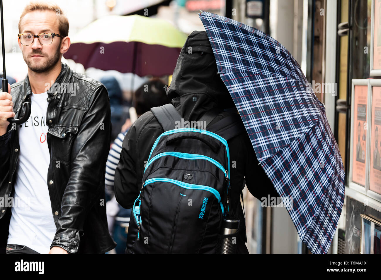 London, UK September 12, 2018 People walking with umbrellas in rainy city weather on sidewalk
