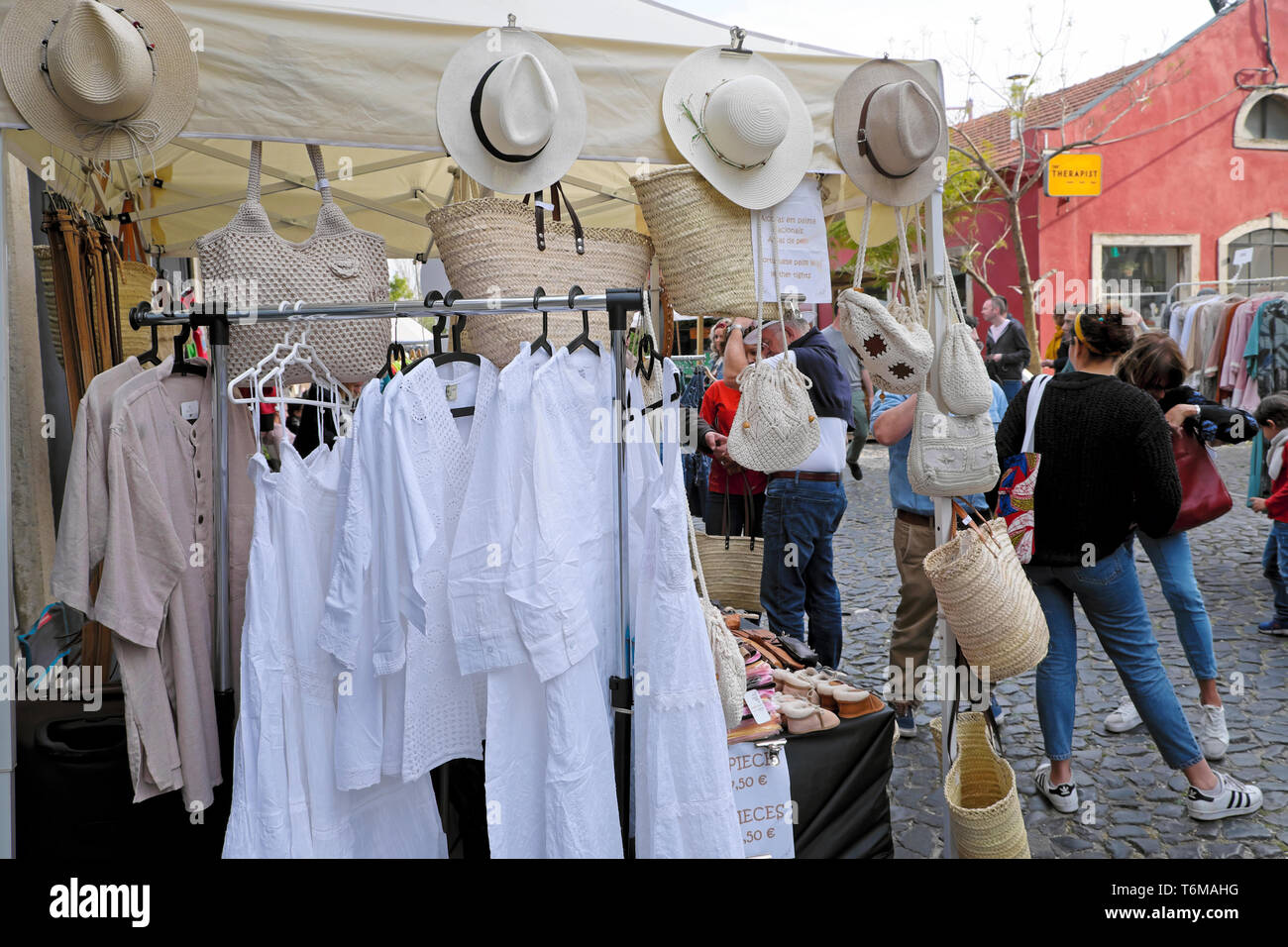 LX Factory street market selling white cotton garments, straw hats