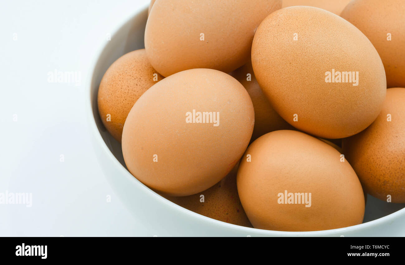 Close up of fresh eggs in a white bowl against a plain white background Stock Photo
