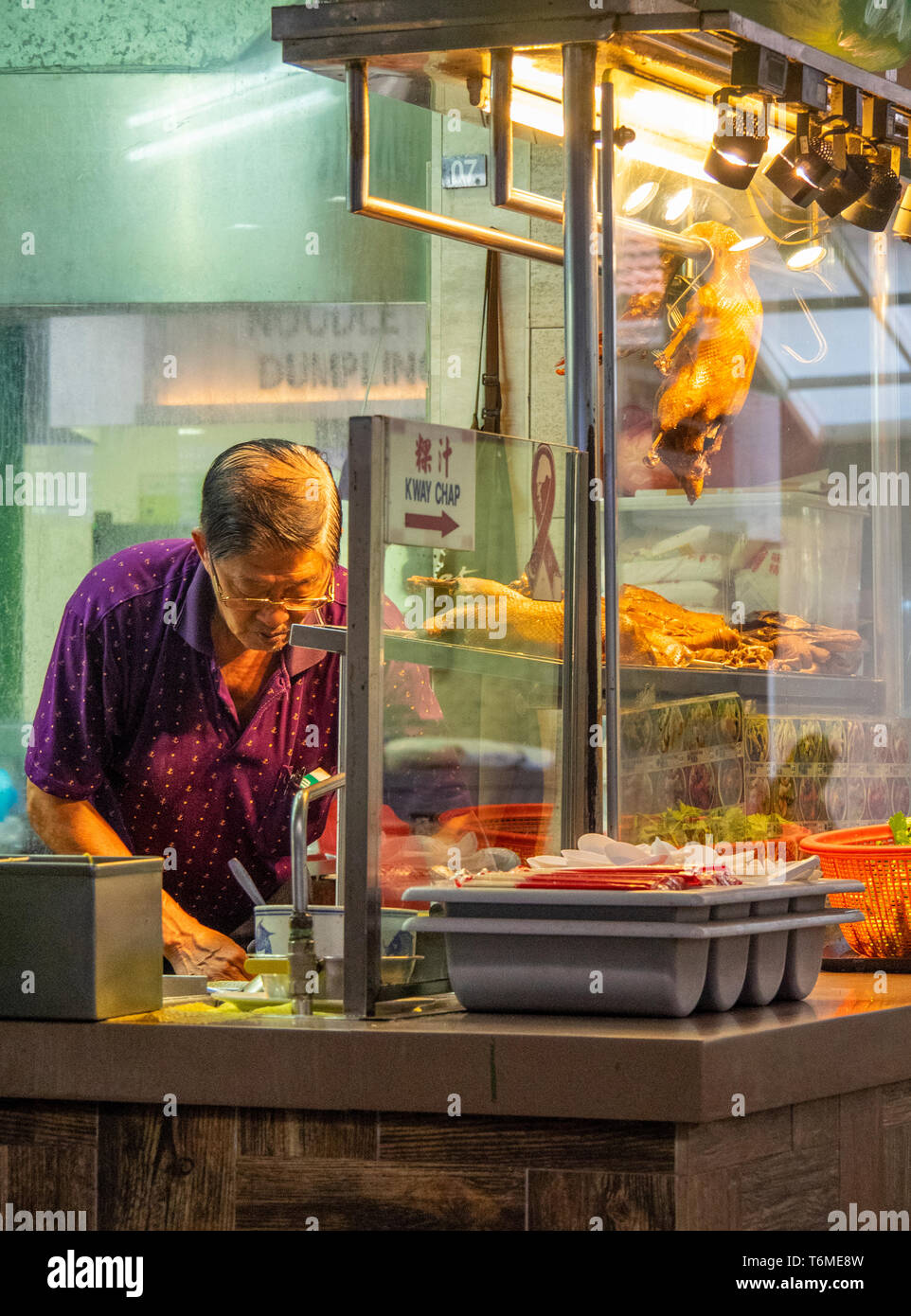 Singaporean man preparing food at a BBQ  restaurant at Lau Pa Sat hawker food markets downtown Singapore. Stock Photo