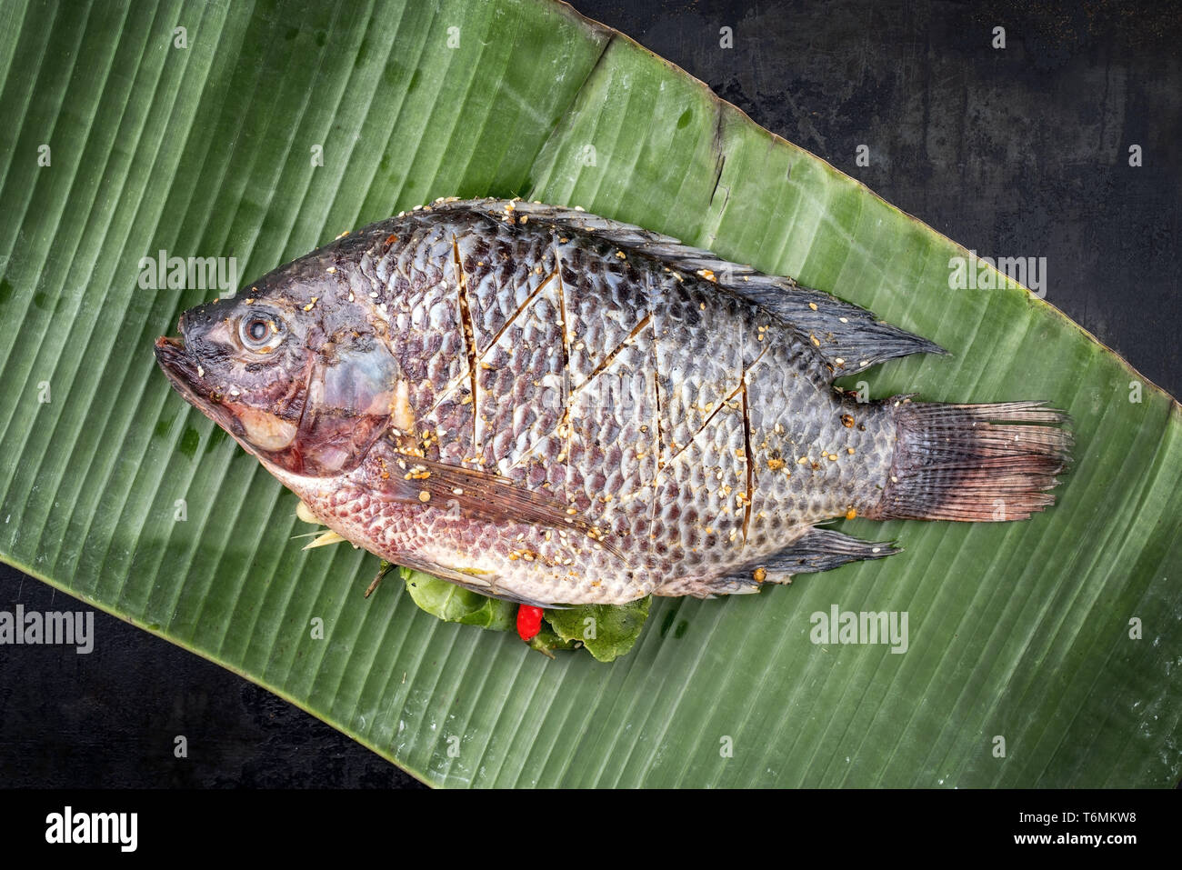 Traditional Thai barbecue tilapia fish staffed with line lemon grass ...